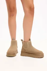 Bota tipo chelsea color camel, confeccionada en gamuza con interior forrado en piel sintética. Presenta elásticos laterales, tirador en la parte trasera y plataforma alta con suela dentada.