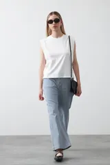 Pantalón de mujer de tiro medio, pierna amplia y recta, confeccionado en tela de algodón a rayas verticales finas celestes y blancas. Presenta bolsillos utilitarios grandes en la parte delantera.