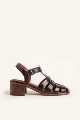 Sandalias de cuero color bordó con tiras entrecruzadas, taco de madera y hebilla lateral.