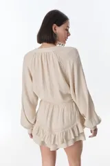 Camisa beige de manga larga con botones y detalles de encaje.