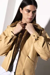 Chaqueta bomber de cuero color marrón, con cuello de piel sintética roja, cierre frontal con cremallera y bolsillos laterales.