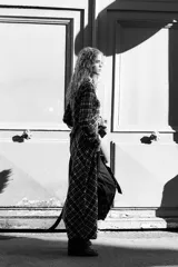Vestido largo tipo camisero con estampado de cuadros en tonos marrón, negro y blanco. Tiene cuello solapa, mangas largas con puños abotonados, dos bolsillos de parche con solapa en el pecho y cierre frontal con botones a presión.