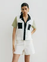 Camisa de manga corta color crudo con estampado de lunares negros, cuello clásico, cierre frontal con botones negros y dos bolsillos de parche en el pecho.