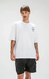 Remera blanca de corte oversize con estampado de Chucky y elementos relacionados al personaje, como armas y un muñeco vudú.