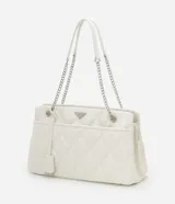 Bolso de hombro mediano color blanco con diseño acolchado en forma de rombos. Tiene asa de cadena plateada, cierre de cremallera y bolsillo frontal con botón a presión.