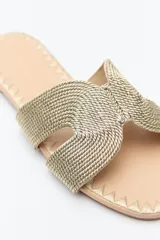 Sandalia baja negra con capellada trenzada tipo cordón, suela plana con bordado a tono.