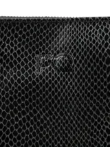 Cartera bandolera negra con textura símil piel de serpiente, confeccionada en cuero. Tiene correa larga regulable, cierre superior con cremallera y logo PQ grabado en el frente.