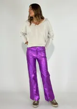 Pantalón metalizado morado con corte acampanado y cierre frontal de botón.
