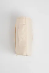 Neceser de viaje color beige con cierre de cremallera y asa de mano. Tiene un pequeño logo rectangular en el frente.