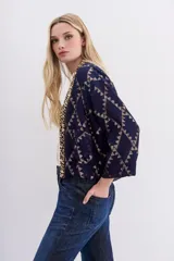 Kimono corto azul marino con estampado geométrico dorado, confeccionado en viscosa jacquard con lurex. Presenta guarda bordada en piedras y canutillos, y forrería interior.
