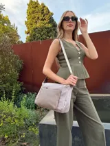 Bandolera de diseño moderno, color beige rosado, con correa regulable y bolsillo frontal con cierre.