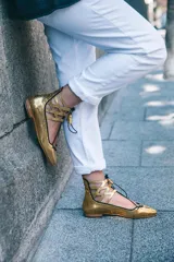 Botines dorados con estampado de escamas, con cordones negros y detalles calados.