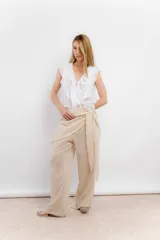 Blusa blanca de algodón con escote en V, volados en el frente y mangas cortas.