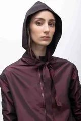 Capucha deportiva color borgoña, confeccionada en tafeta tornasolada con tiras ajustables que pueden anudarse formando un lazo.