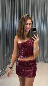 Top corto de fiesta color borgoña, con un solo hombro y lentejuelas.