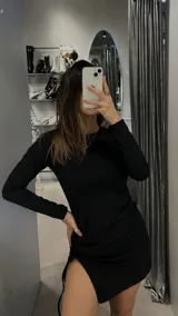 Minivestido negro de manga larga, corte ajustado y falda con abertura lateral y frunce.