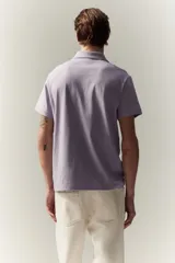 Remera polo lila de punto de algodón liviano, corte ajustado, manga corta, cuello clásico con tapeta de botones y bajo recto.