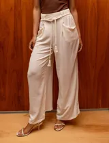Pantalón palazzo color crudo, marca Dictionary. Con pretina ancha elastizada con pasadores y cinto de cordón. Delantera con bolsillos.