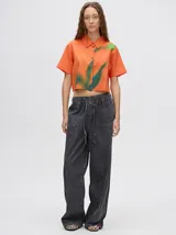 Camisa crop naranja con estampado abstracto en tonos verdes y azules, de corte recto y mangas cortas.