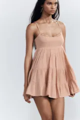Vestido corto color salmón, de escote recto y tirantes finos ajustables. Presenta detalle de encaje en el escote y falda de tres niveles.