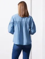 Blusa celeste de lyocell con cuello a la base, escote en V con botones y mangas 3/4 con puño abotonado.