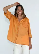 Camisa color naranja con cuello con detalle de puntilla, manga 3/4 y bolsillo en el pecho.