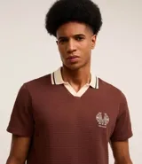 Camisa polo marrón con textura, cuello con detalle contrastante en beige y logo bordado en el pecho.