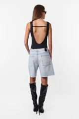Bermuda de jean celeste con roturas, tiro medio, terminación al corte con pespunte de seguridad, cintura con pasacintos, cartera de cierre y botón metálico personalizado.