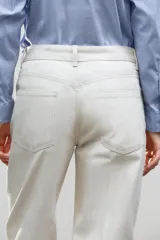 Pantalón de jean color crudo, de tiro medio, corte tapered, con cinco bolsillos y raya planchada en el frente.