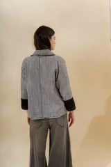 Saco color arena con solapas, bolsillos frontales y mangas 3/4 con puños en gris oscuro.