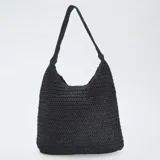Bolso hobo negro de tejido de paja o rafia trenzada, con asas cortas anudadas al hombro.