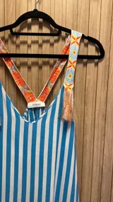 Vestido solera largo de algodón con estampado de rayas verticales en color naranja y blanco. Breteles con detalle de bordado floral y flecos.