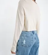 Blusa cropped de punto color negro, con cuello redondo, manga larga y sisa desplazada.