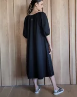 Vestido midi celeste de denim, con escote con lazo, mangas 3/4 abullonadas y corte evasé.