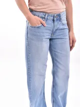 Pantalón jean celeste de corte recto, con cintura alta y detalles de roturas en los bolsillos delanteros.