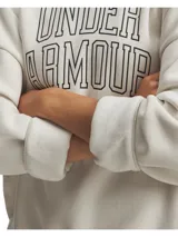 Buzo Under Armour de mujer, modelo Rival Fleece Oversized, color blanco hueso con logo Under Armour en el frente. Corte holgado y tejido polar suave.