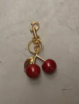 Charm en forma de cereza roja con acabado brillante y detalles en dorado.