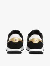Zapatillas Tommy Hilfiger negras con detalles en blanco y dorado. Confeccionadas en poliéster con interior de poliéster, plantilla extraíble de goma termoplástica reciclada y suela de EVA. Presentan paneles con mezcla de texturas, panel metalizado en el talón y logo de Tommy Hilfiger bordado en la lengüeta y el talón.