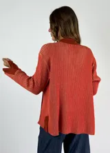 Saco de punto color crudo con cuello camisero, cierre frontal con botones y bolsillos de parche.
