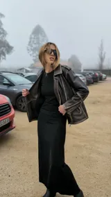Chaqueta de cuero ovino color marrón, con cuello clásico, cierre asimétrico con cremallera, solapas con botones a presión, múltiples bolsillos con cremallera y cinturón ajustable en la cintura.