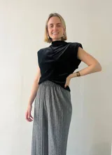 Blusa sin mangas de terciopelo negro con cuello alto y hombreras.