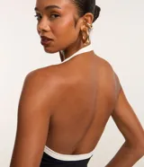 Body de mujer color negro con escote en V profundo y tirantes tipo halter en contraste blanco.