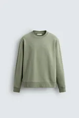Sudadera verde militar de algodón con interior de rizo, corte relaxed fit, cuello redondo y mangas largas con puños y ruedo acanalados.