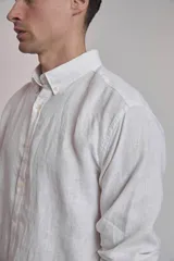 Camisa blanca de lino con cuello abotonado, manga larga con puños abotonados y corte clásico.