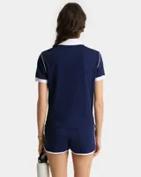 Polo de piqué azul marino con cuello blanco, corte entallado y logo bordado en el pecho.