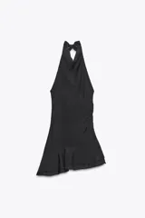 Vestido corto negro de tejido fluido con cuello halter que se ata con lazada. Tiene forro interior, detalle de frunces y bajo asimétrico con volantes. Cierre lateral con cremallera oculta.