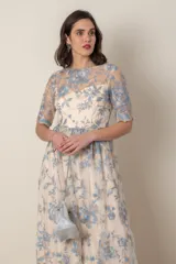 Vestido largo de gasa color marfil con bordado de hilo de seda en tonos celeste y avena. Modelo recto con corte en la cintura, manga corta y ruedo terminado en blonda.