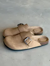 Zuecos color beige con hebilla metálica ajustable, plantilla anatómica y suela de corcho.