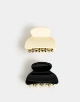 Set de dos broches para el pelo tipo pinza, uno color crema y otro negro, ambos con dientes dorados.