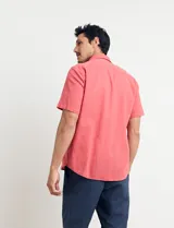 Camisa sport de manga corta color verde oliva, línea premium, con cuello clásico, cierre frontal con botones de coco y bolsillo de parche en el pecho. Confeccionada en lino y algodón.